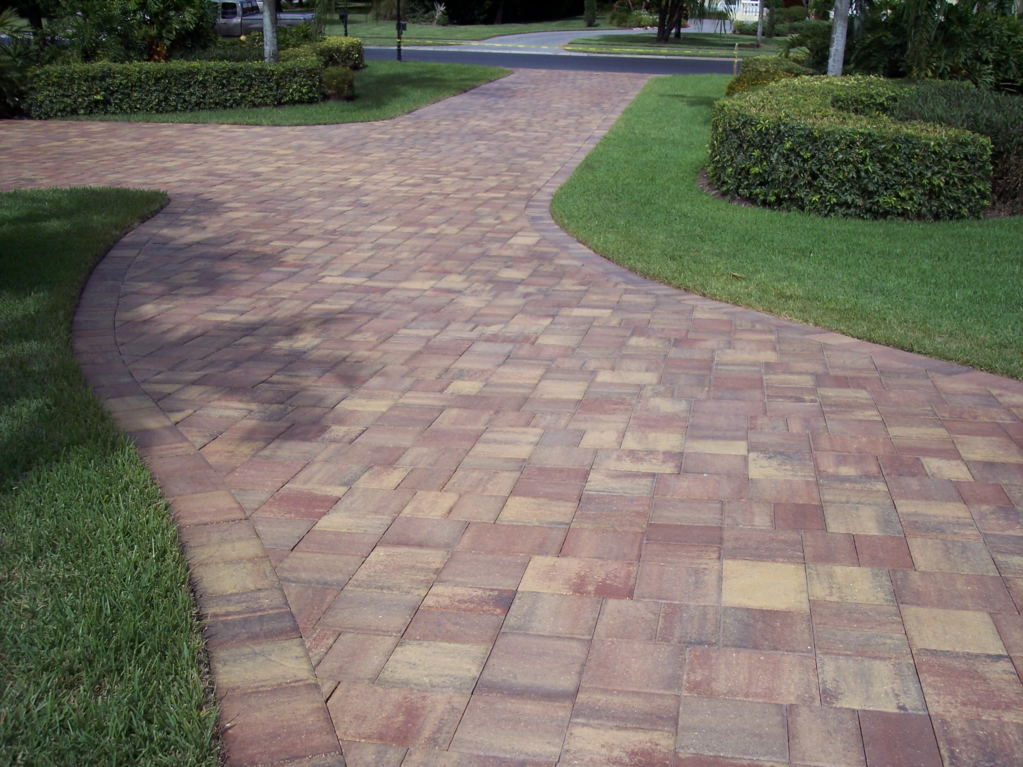 Curving paver driveway with a coordinated border beside a lawn