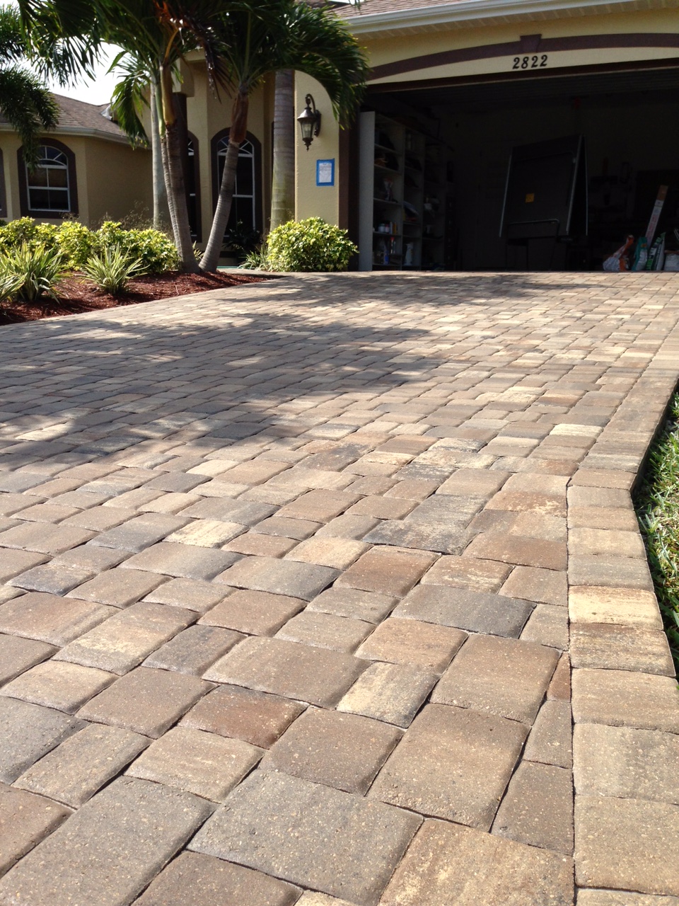 Tan and brown driveway pavers with a defined edge beside a garage