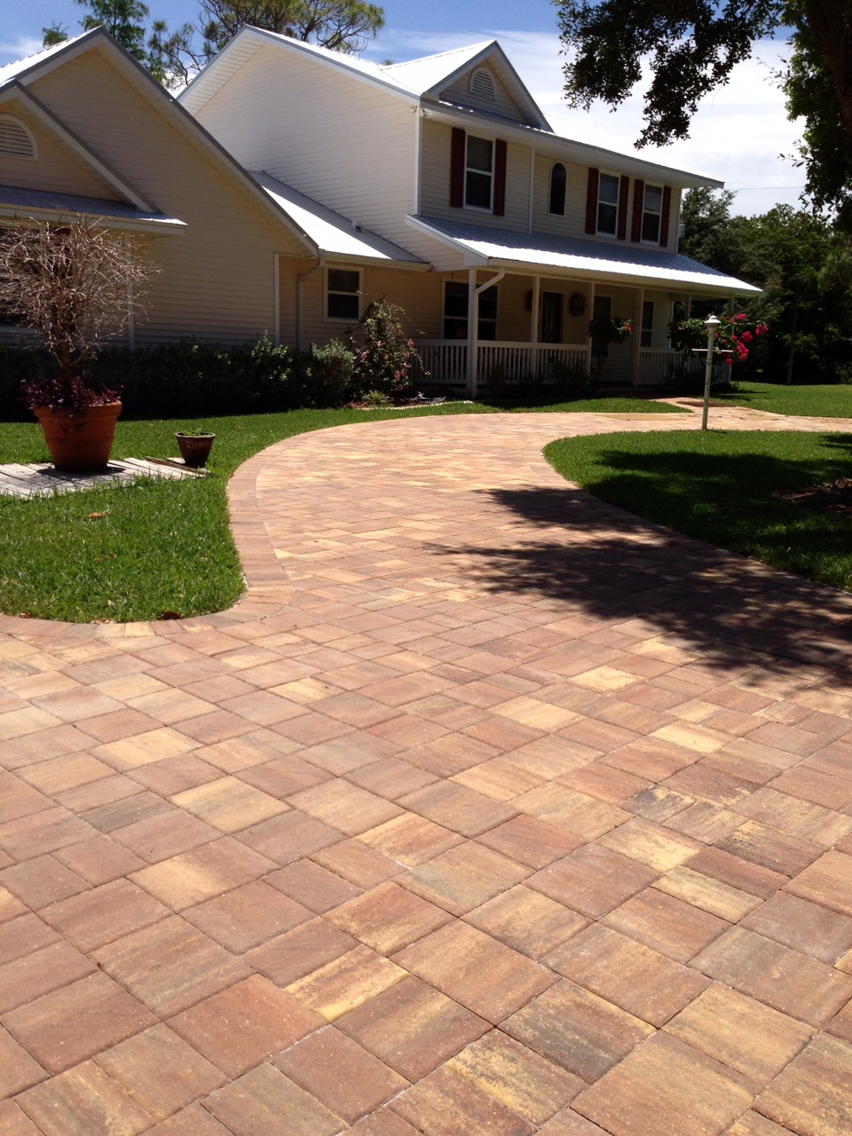Warm blended curved paver driveway in front of a two-story home